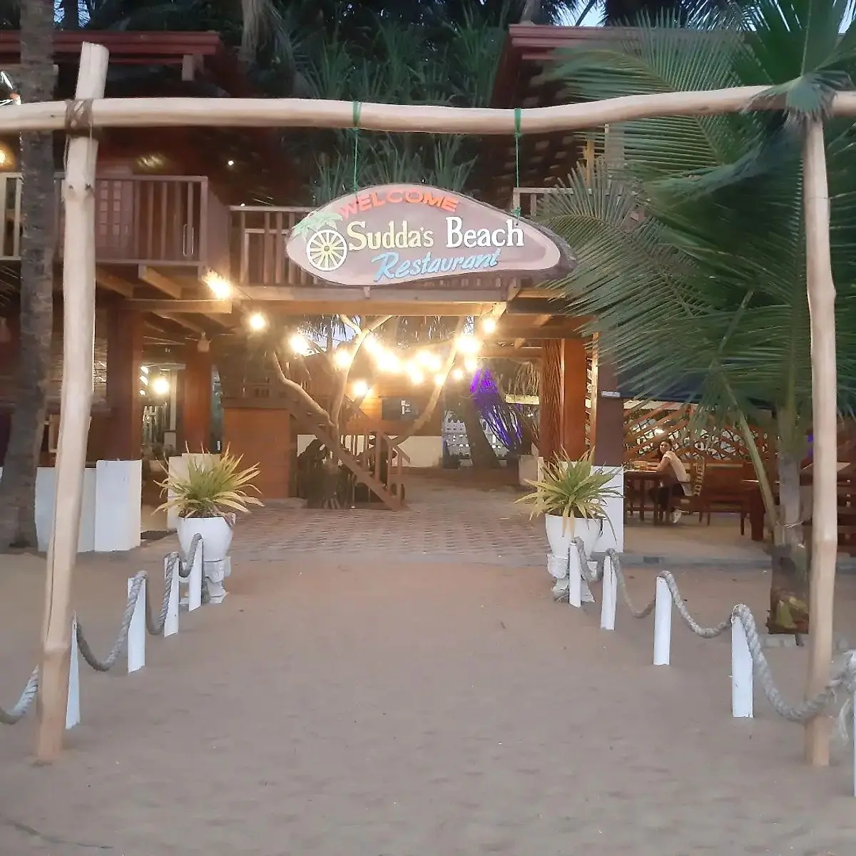 Sandy entrance path lit with fairy lights leading into Sudda's Beach Restaurant
