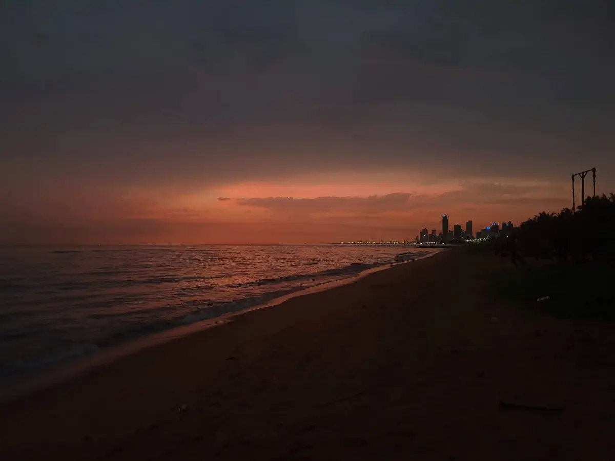 Orange sunset over the sea along the Dehiwala coastline, Colombo skyline in the distance