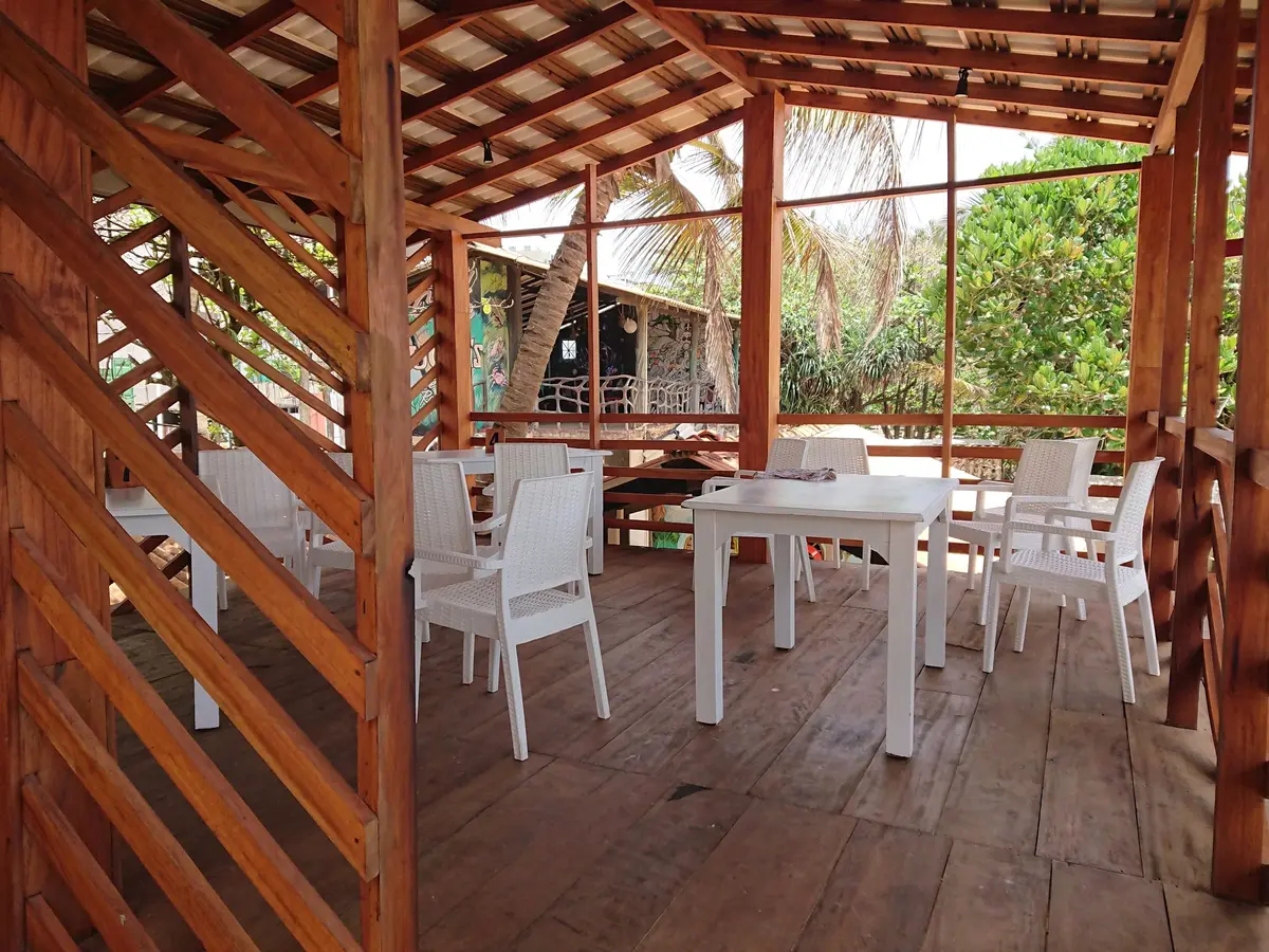 Timber dining deck with white tables and chairs set among greenery
